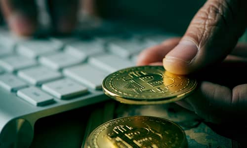 Young man holding a coin and using computer keyboard