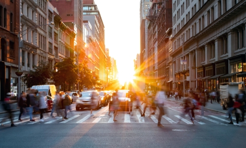 View of a busy street with cars and people walking