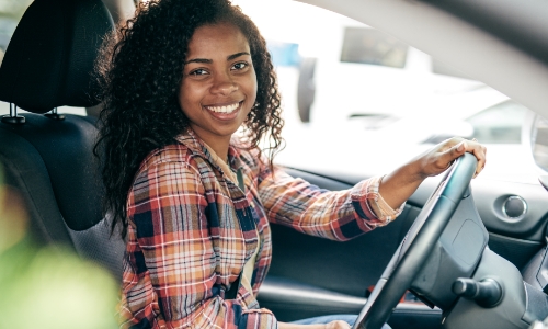 Young person sitting in the driver's seat of a car