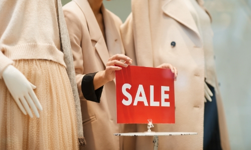 Employee placing a sale sign in store window