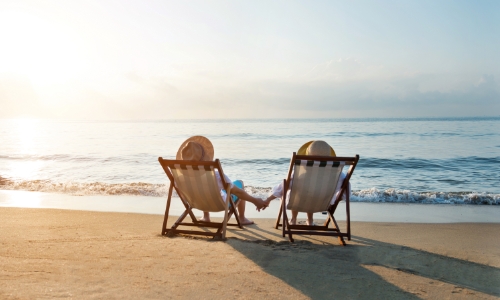 Newlyweds sitting in chairs on the beach