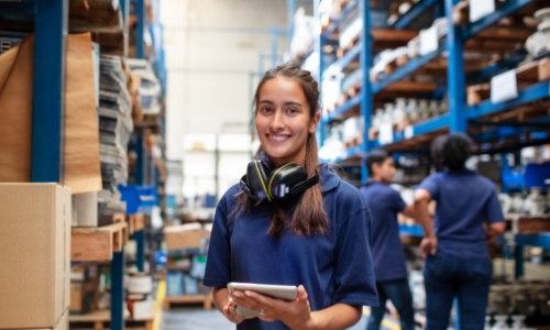 A girl standing in a warehouse taking inventory