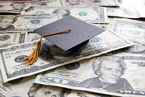 A graduation cap sitting on top of a pile of cash