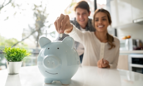 A couple putting coins into a piggy bank