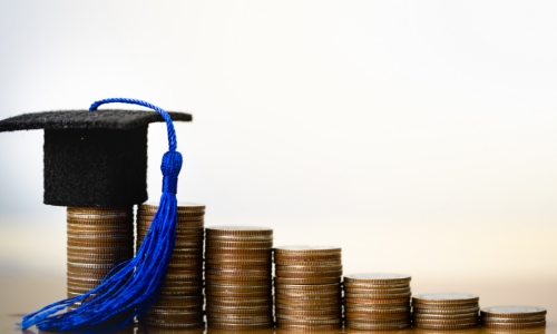 Stacks of coins with a graduation cap on top