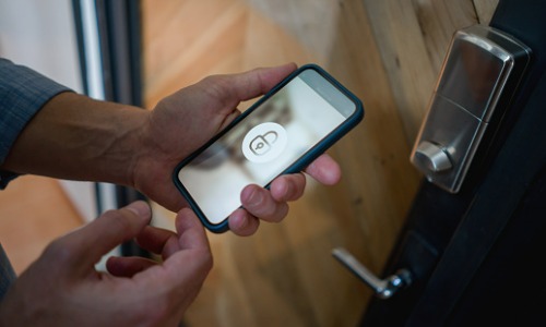 Man opening door of his house using home automation system.