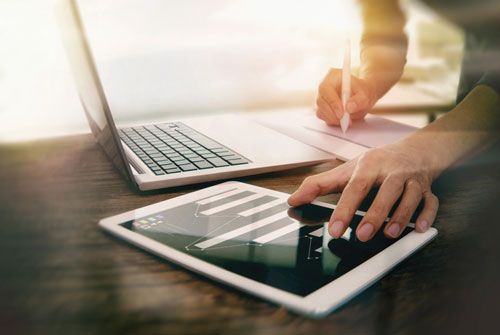 A person is using both a tablet and laptop