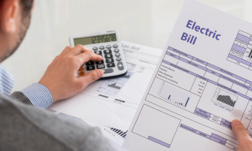 Person looking at electric bill with calculator next to them