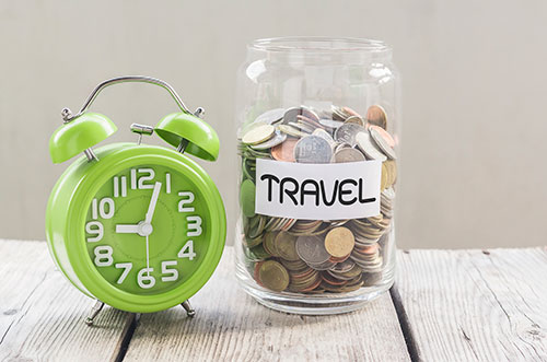 A green alarm clock and a jar of coins