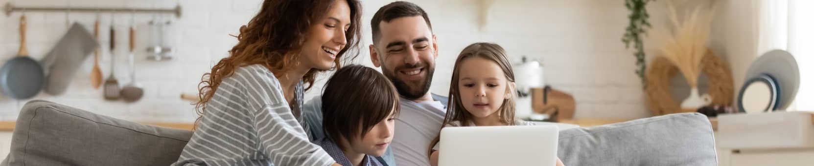 A family sitting on the couch looking at a laptop