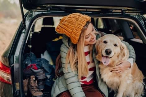 A girl and her dog sitting in the back of a vehicle