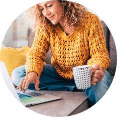 woman sitting down reading computer with coffee